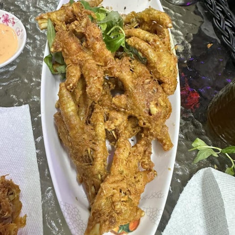 Crispy fried chicken feet with fresh green herbs and a side of dipping sauce.