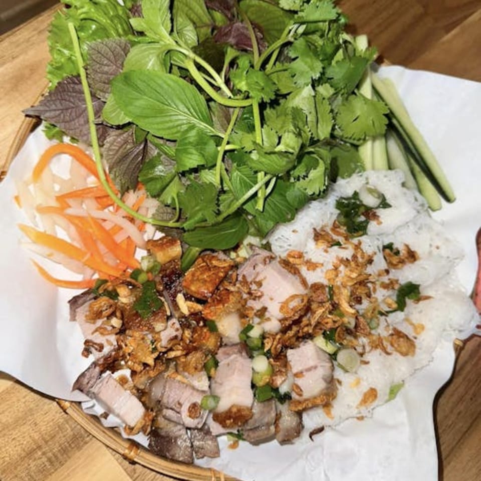 Vietnamese dish with sliced pork, rice noodles, fresh herbs, pickled carrots, and fried shallots.