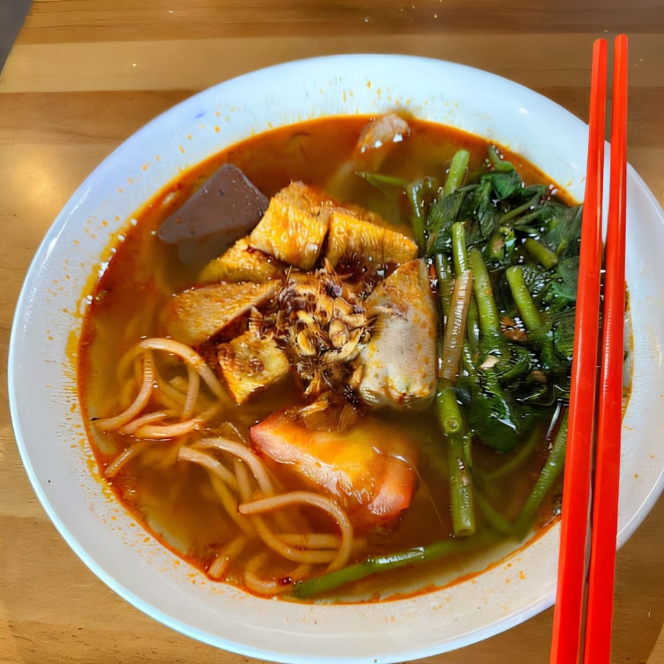 A vibrant bowl of Vietnamese noodle soup with various toppings and red chopsticks.