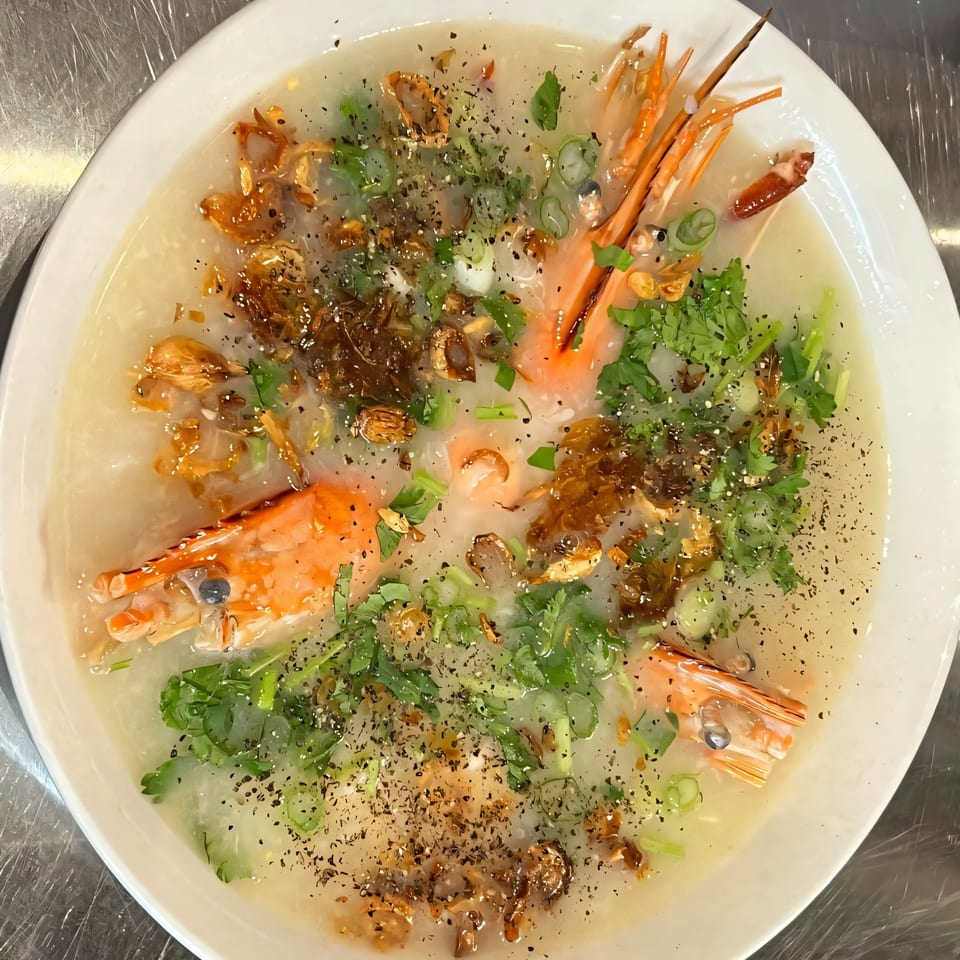 Vietnamese shrimp and crab congee, garnished with herbs, fried shallots, and black pepper.