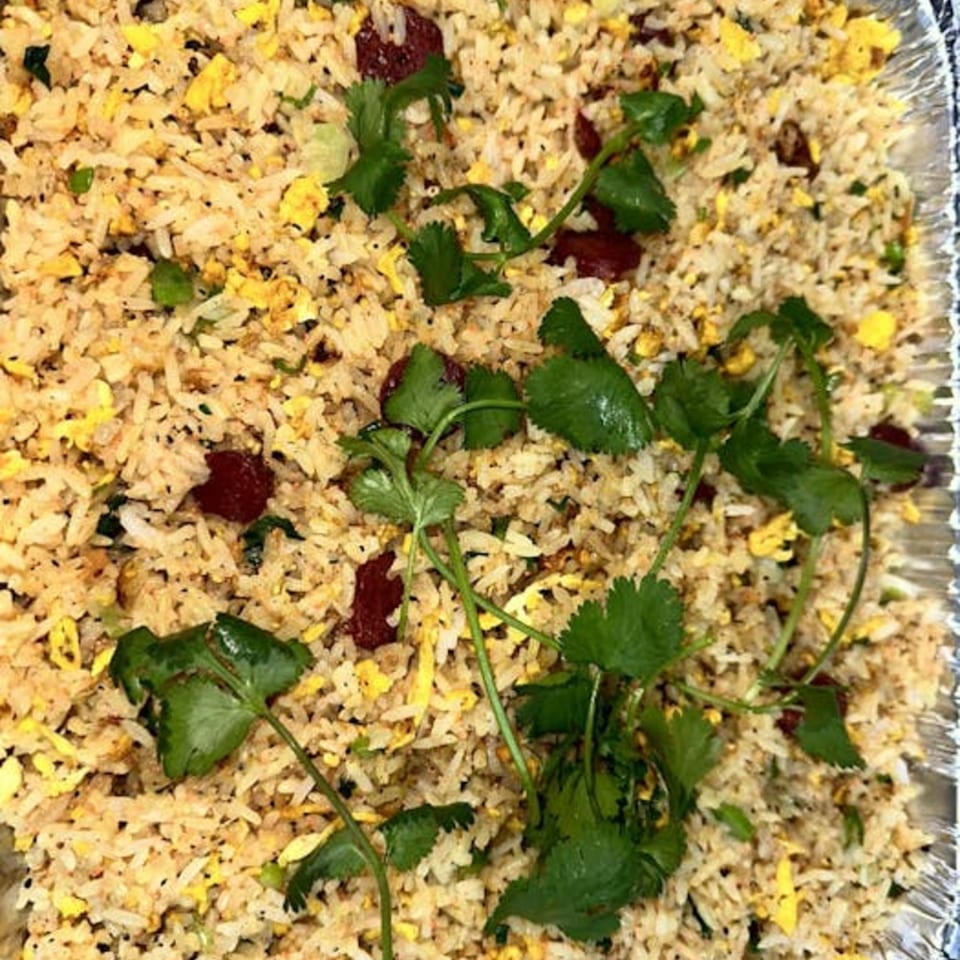 Vietnamese fried rice with scrambled egg, dark meat, and fresh cilantro in a foil container.